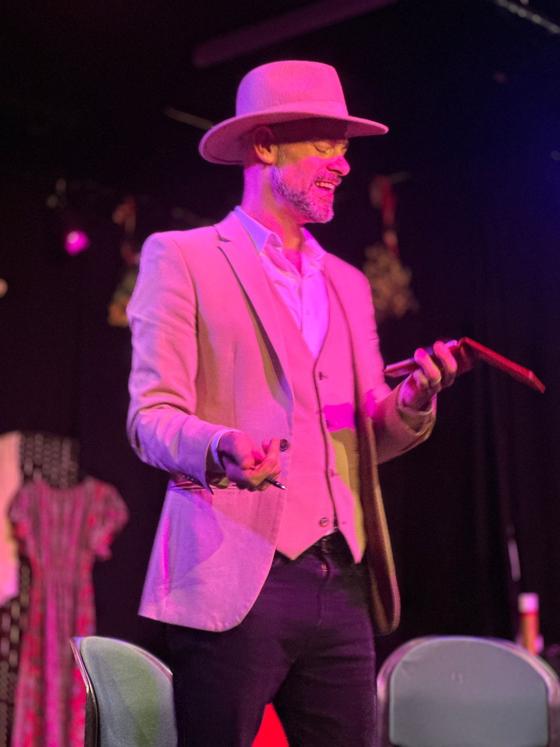 Peter Rae performing onstage under pink theatrical lighting
